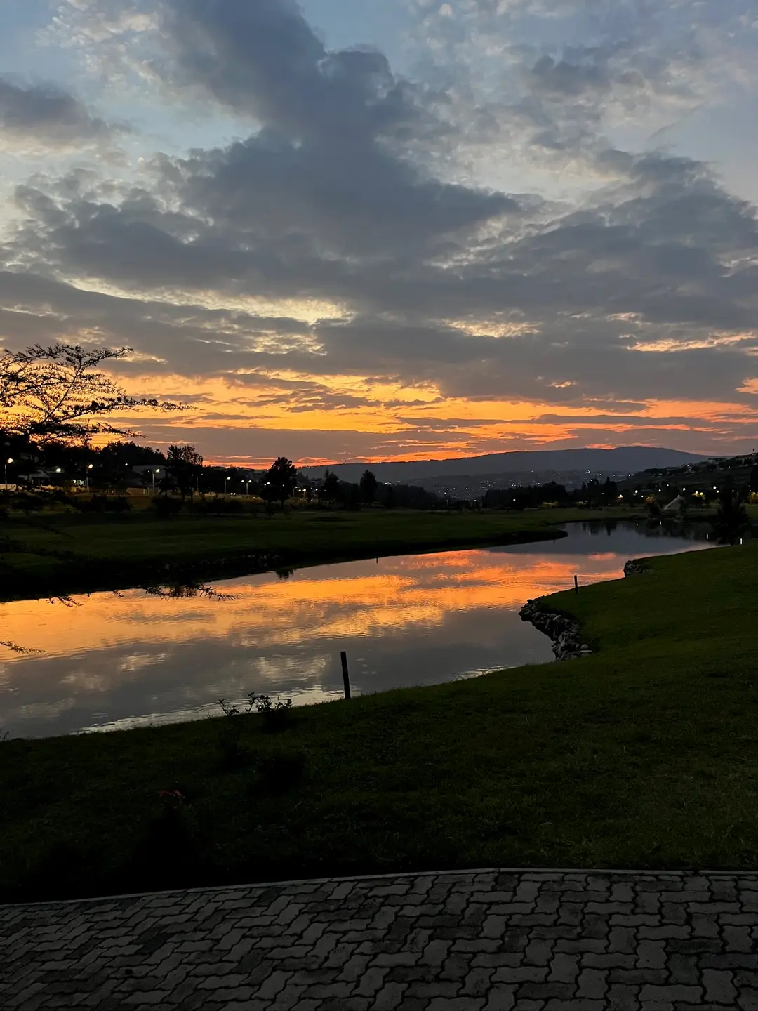 Sonnenuntergang über See mit Hügeln im Hintergrund